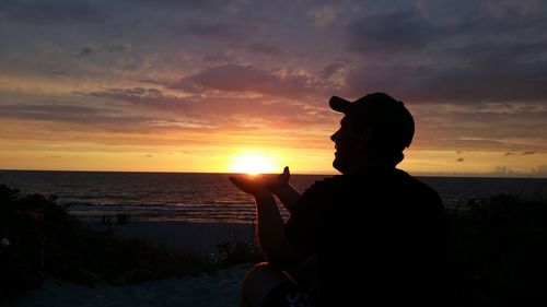 Silhouette man on beach against sky during sunset