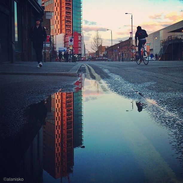 building exterior, architecture, built structure, city, lifestyles, men, street, city life, walking, leisure activity, sky, person, full length, water, city street, wet, building, weather