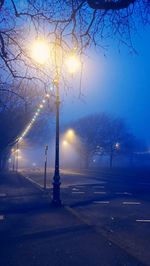 Illuminated street light on snow covered road at night