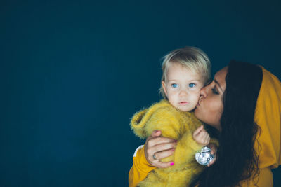 Woman kissing daughter against black background