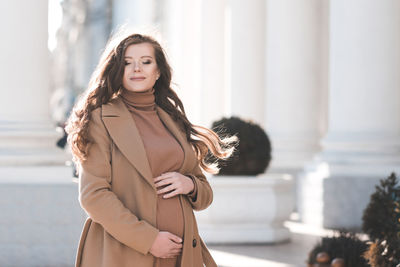 Smiling pregnant woman standing on street