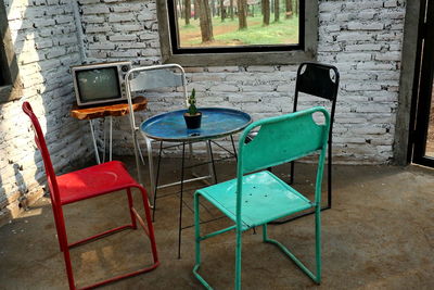 Empty chairs and table against window in old building