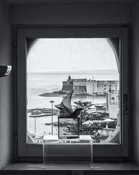 View of sculpture and sea seen through window