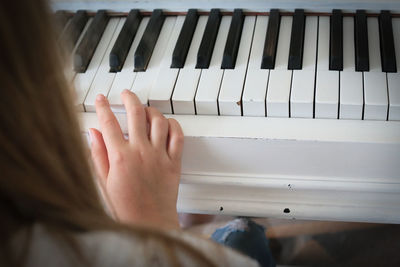 Cropped image of woman playing grand piano at home