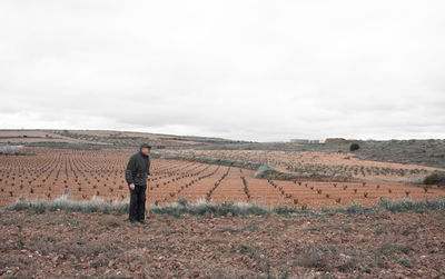 Old farmer is resting on his hoe after working in his wine field person