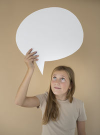 Portrait of smiling young woman standing against wall