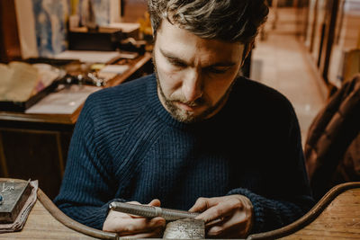 Young man looking down while sitting on table