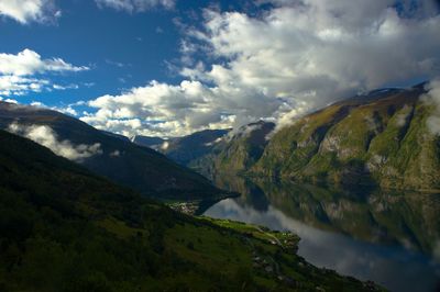 Scenic view of mountains with river against cloudy sky