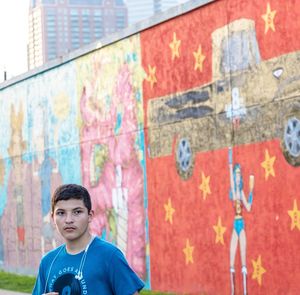 Portrait of boy standing against graffiti wall