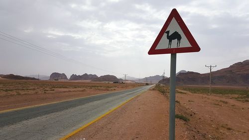 Road passing through landscape against cloudy sky