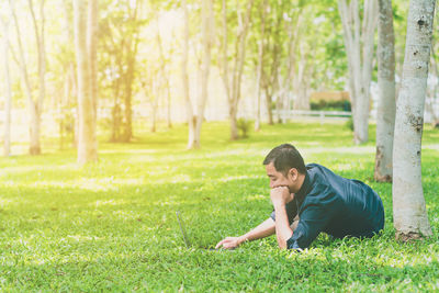 Mid adult man using laptop while lying on grassy field at park