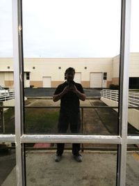 Man standing by window against clear sky