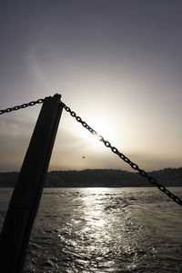 Silhouette of chain by sea against sky during sunset