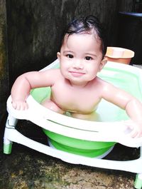 Portrait of naked cute baby girl sitting in bathtub