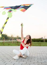 Woman holding umbrella while standing against sky