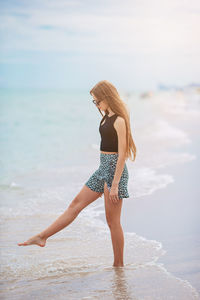 Rear view of woman standing at beach