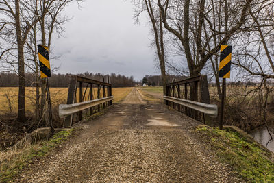 Road amidst bare trees against sky