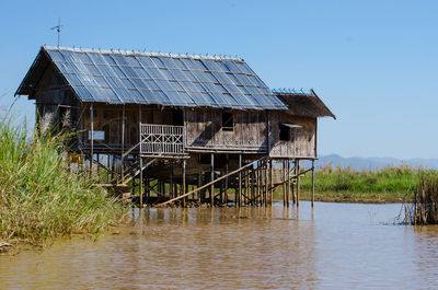 Stilt house in lake against clear sky