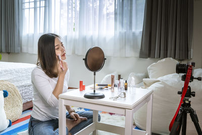 Young woman sitting on table at home