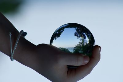 Cropped image of person holding glass against sky