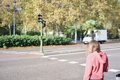 Rear view of girl standing on road