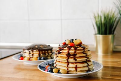 Close-up of pancakes with fruits in plate on table