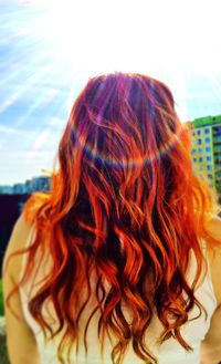 Rear view of redhead girl against cloudy sky