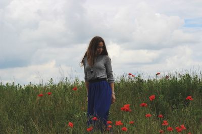 Woman standing on field against cloudy sky