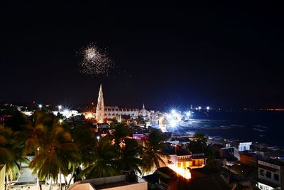 Firework display over city against sky at night