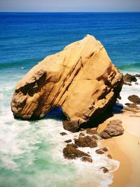 Rock formation on beach against sky