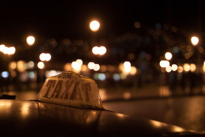 Taxi sign with lights in the background