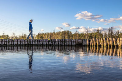 Man standing by lake against sky