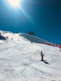 Woman skiing on snowcapped mountain against sky on sunny day