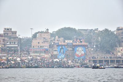 Sailboats in river against buildings in city