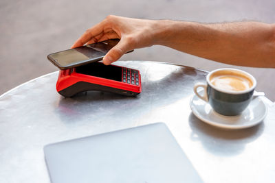 Cropped image of hand holding coffee cup on table