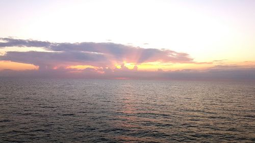 Scenic view of sea against dramatic sky during sunset