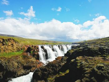 Scenic view of waterfall in forest against sky