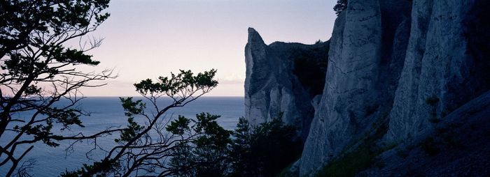 Scenic view of sea by silhouette mountain against sky