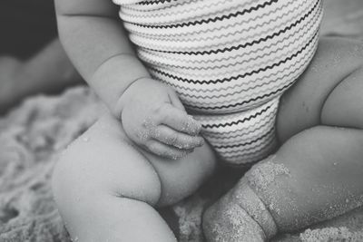 Midsection of baby girl sitting on sand at beach