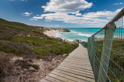 Wooden walkway leading to indian ocean beach, de hoop nature reserve, south africa against sky