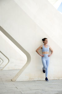 Woman leaning against a concrete wall resting during training,