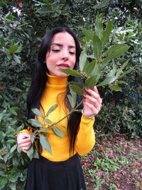 Beautiful young woman standing by flowering plants