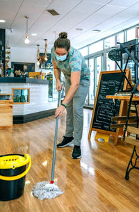 Waiter wearing mask cleaning floor in cafe