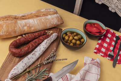 Spanish fuet salami and fresh sage on rustic wooden cutting board.