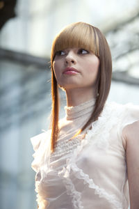 Low angle view of beautiful young woman looking away while standing outdoors