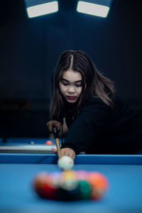 Portrait of young woman playing pool