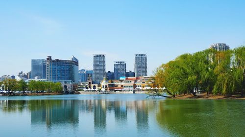 Scenic view of river by buildings against clear sky