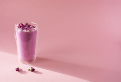 Pink rose milk with rose petals in a double walled glass. healthy drink moon milk. copy space.