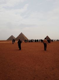 People walking at great pyramid of giza against sky