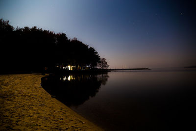 Scenic view of lake against clear sky at night